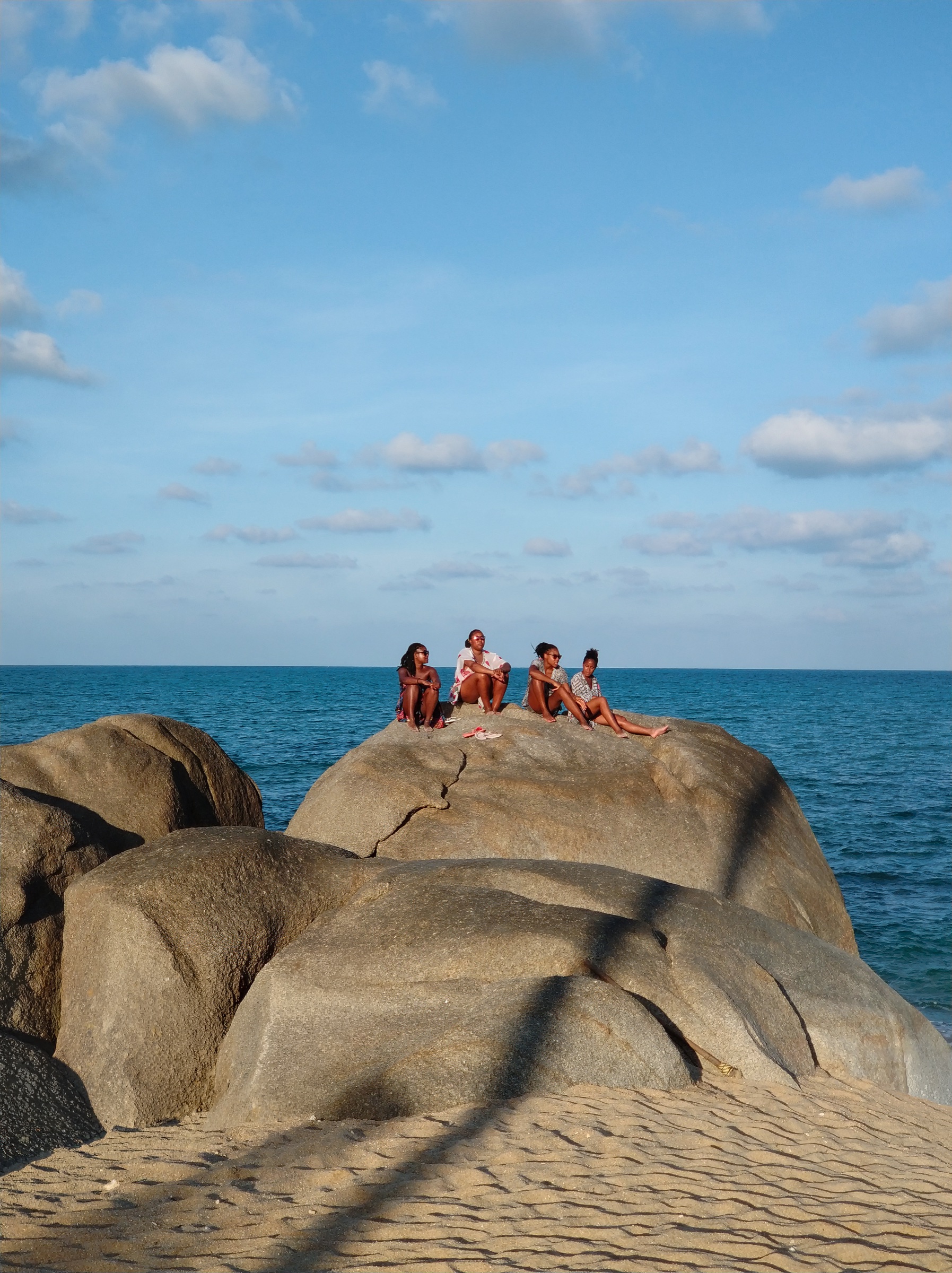 Figures gathered on rocks beside the sea